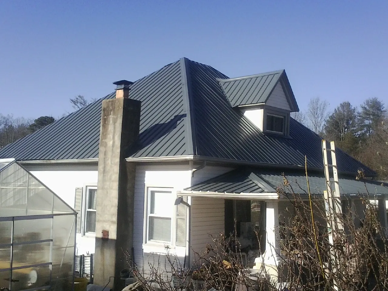 Dark blue standing seam metal roof on a white farmhouse with dormer — Slate & Tile Roof Repair by Roofing Brothers in Bannock