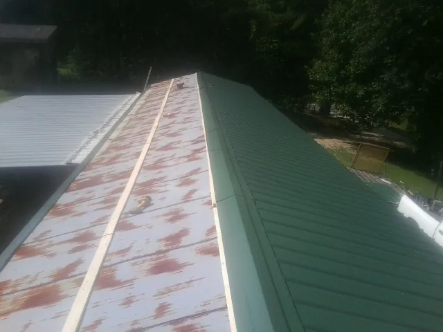 Old rusted panels beside newly installed green metal roofing — Wind Damage Roof Repair by Roofing Brothers in Bannock