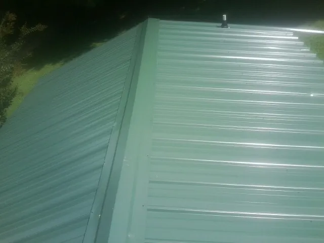 New green metal panels meeting at the ridge of a roof — Flat Roof Repair work by our crew in Bannock