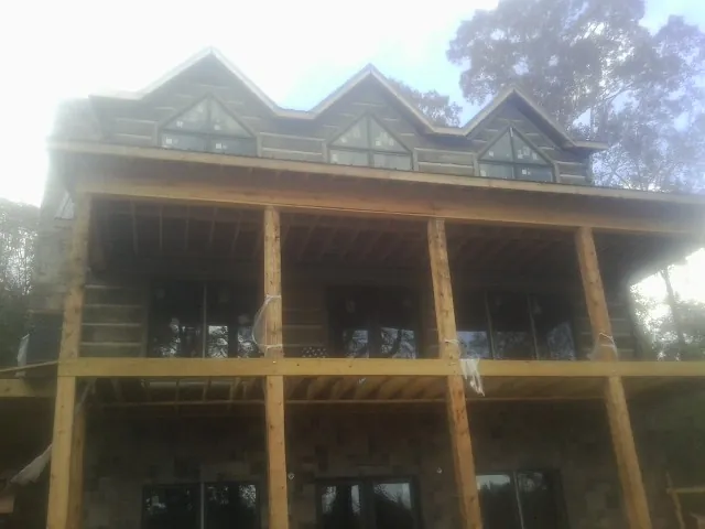 Dormers and porch framing on a large log home under construction — Roof Coating work by our crew in Bannock