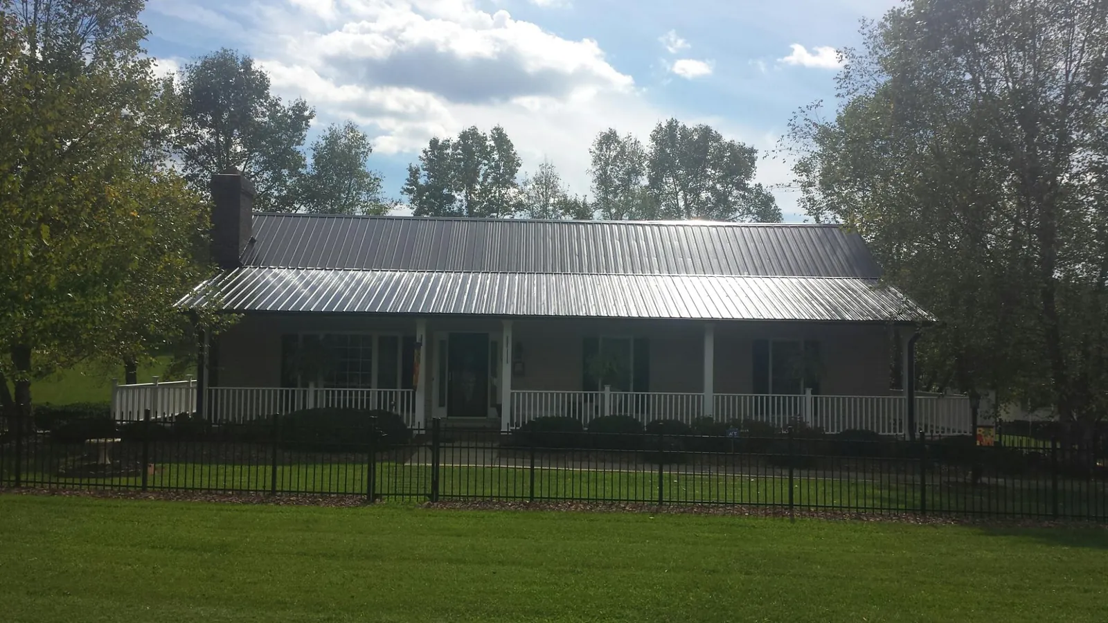Gray metal roof on a brick ranch with a full width front porch — Gutter Guard Installation work by our crew in Bannock