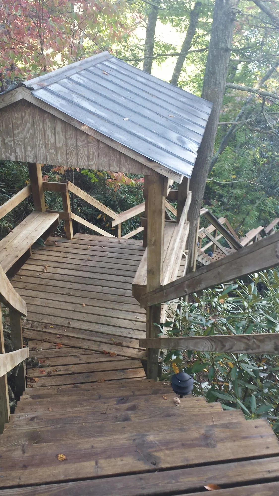 Metal roofed shelter over wooden steps on a wooded walkway — Skylight Repair & Installation work by our crew in Bannock