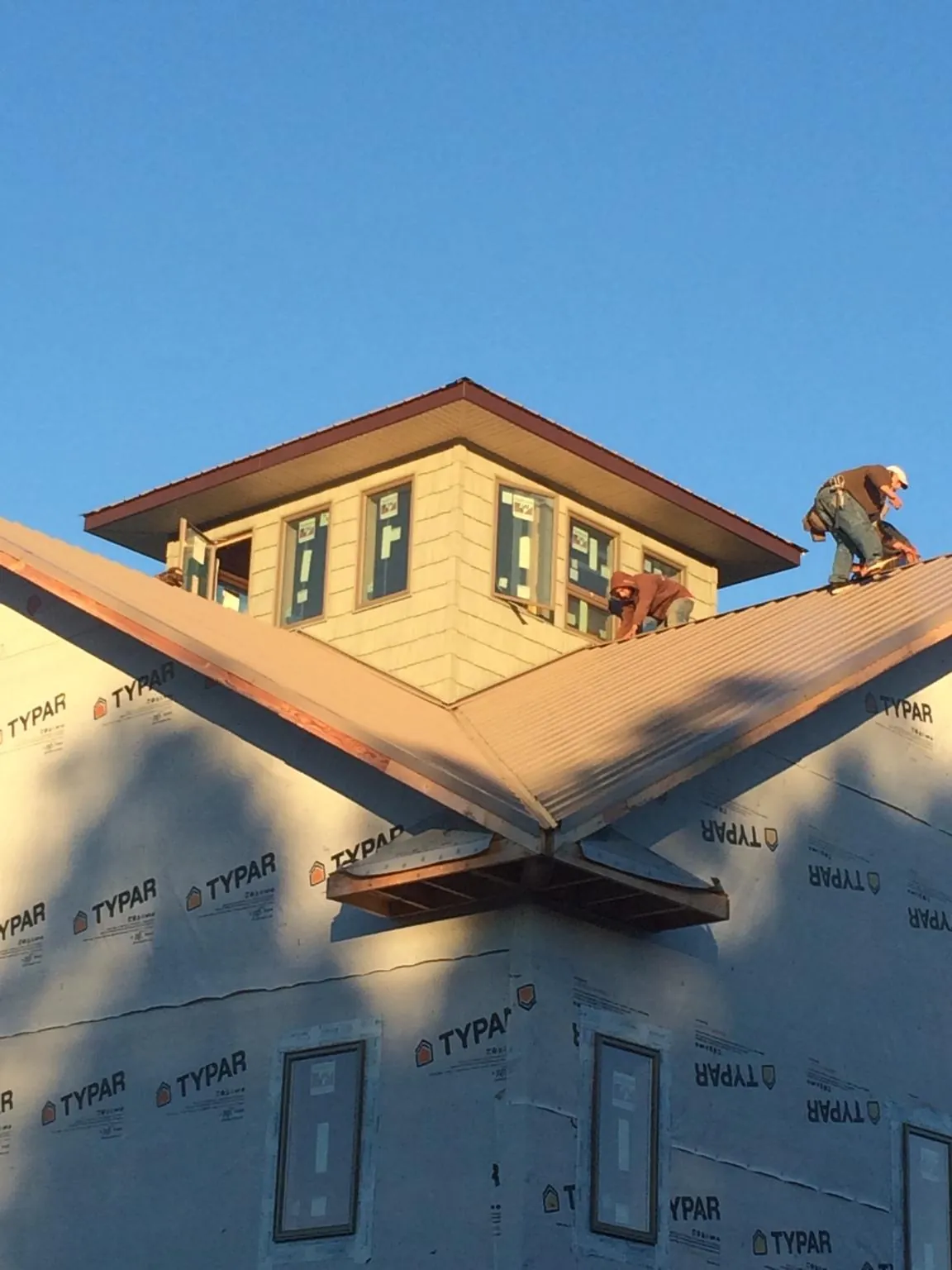 Roofers working around a rooftop cupola on a new metal roof at sunset — Roof Waterproofing in Bannock by Roofing Brothers